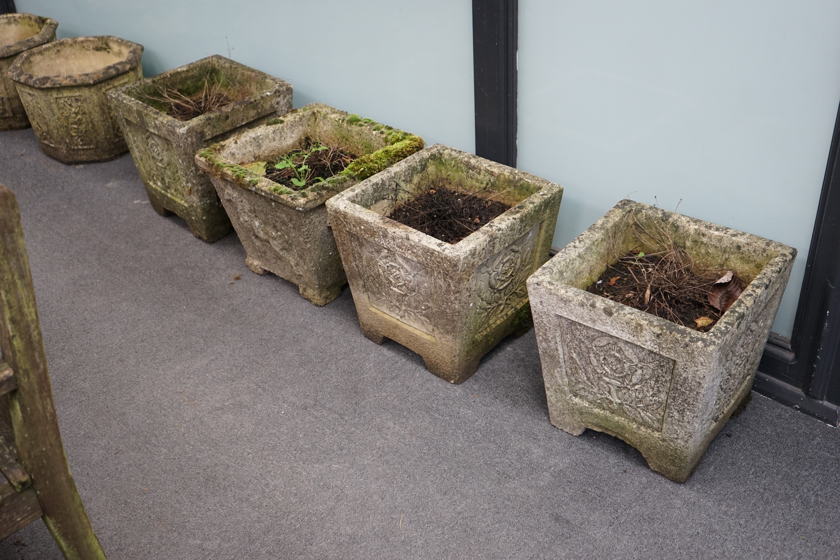 A set of three reconstituted stone garden planters, decorated with Tudor roses, 36cm sq., 37cm high, and a single square planter moulded in relief with a horse